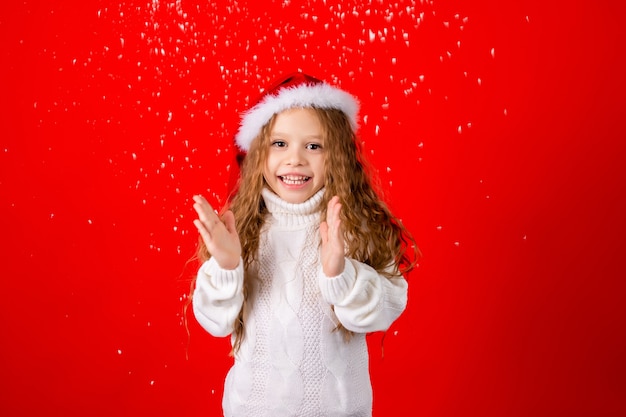 Menina bonitinha com chapéu de Papai Noel e um suéter