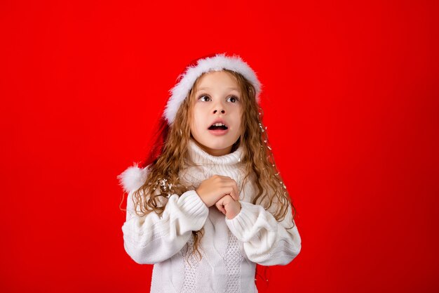 Menina bonitinha com chapéu de Papai Noel e um suéter