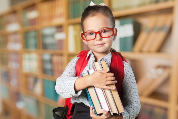 Menina bonitinha com livros no fundo