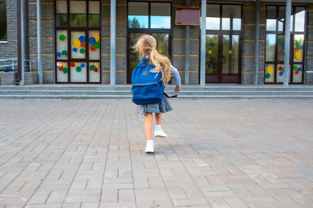 Menina bonitinha com mochila corre de volta para a escola