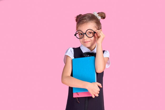 Menina bonitinha com óculos e livros no espaço rosa, espaço para texto