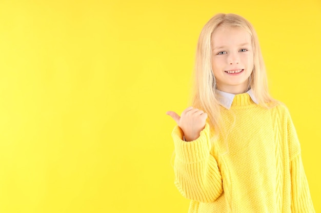 Menina bonitinha com suéter em fundo amarelo