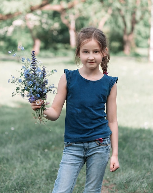 Menina bonitinha com um buquê de flores silvestres