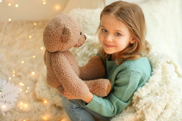 Menina bonitinha com ursinho de pelúcia em casa