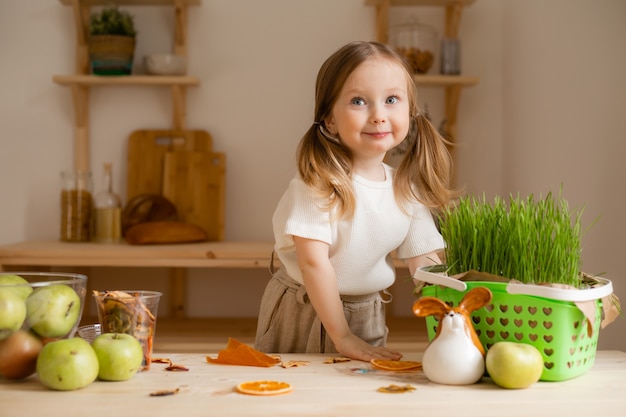 Menina bonitinha come pastilha natural em casa em uma cozinha de madeira.