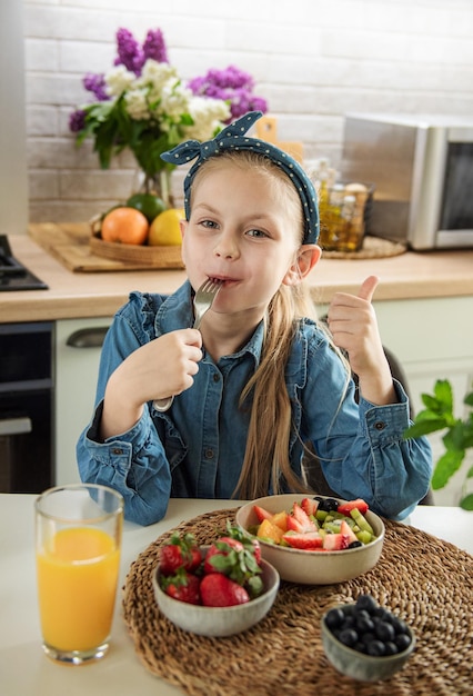 Menina bonitinha come salada de frutas