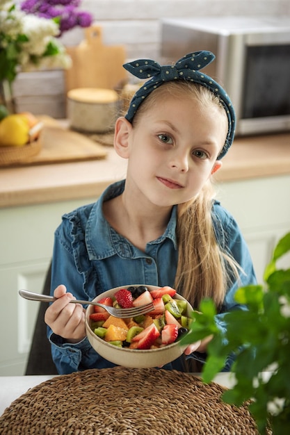 Menina bonitinha come salada de frutas