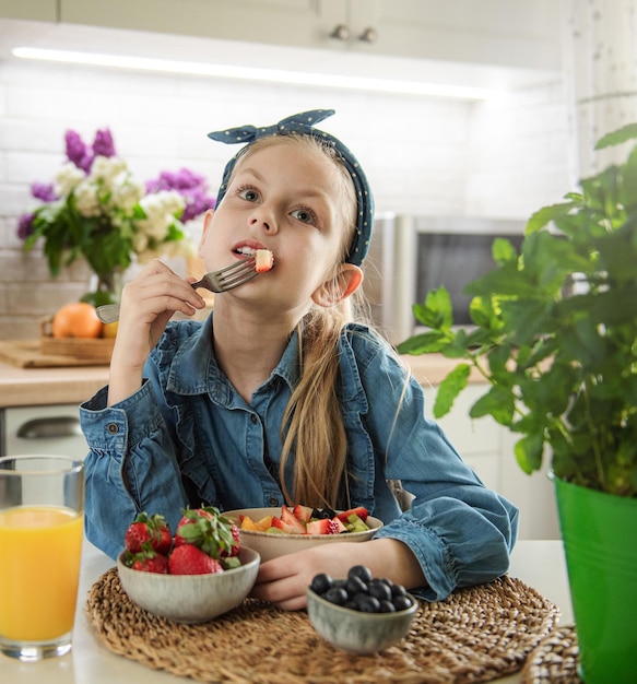 Menina bonitinha come salada de frutas