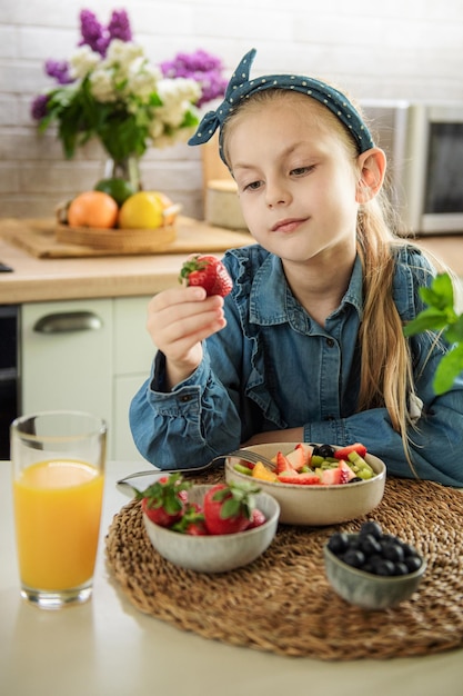 Menina bonitinha come salada de frutas