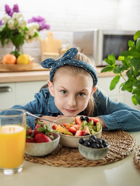 Menina bonitinha come salada de frutas