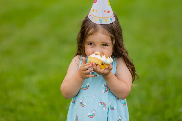 Menina bonitinha comendo bolo no parque aniversário feliz cartão saúde