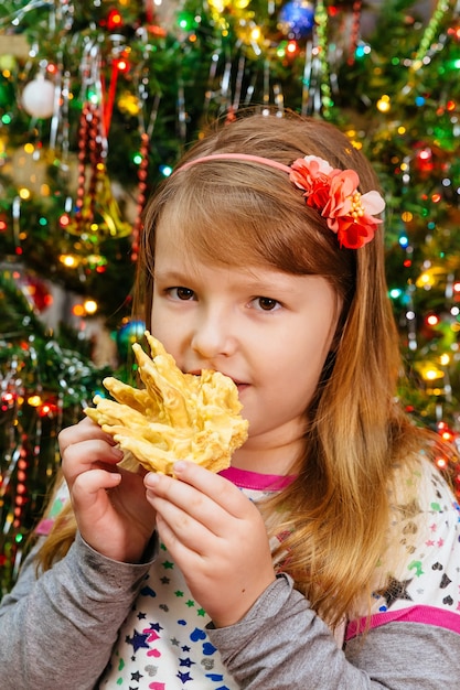 Menina bonitinha comendo bolo sakotis ano novo e fundo de feliz natal