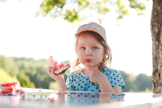 Menina bonitinha comendo melancia ao ar livre no verão criança e melancia no verão