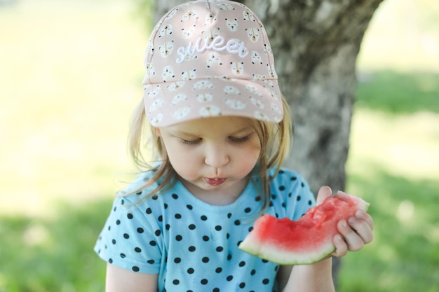 Menina bonitinha comendo melancia ao ar livre no verão criança e melancia no verão