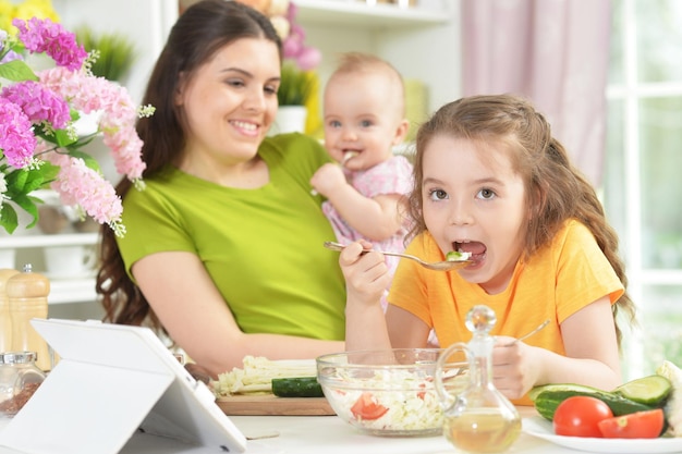 Menina bonitinha comendo salada fresca na mesa da cozinha