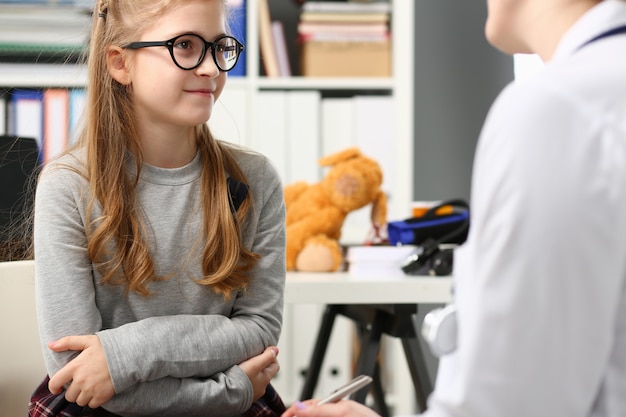 Foto menina bonitinha conversando com o médico na clínica