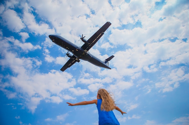 Foto menina bonitinha criança olhando para o céu e voar de avião diretamente acima dela