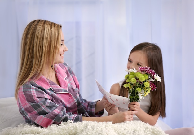 Menina bonitinha cumprimentando a mãe em casa. Conceito do dia das mães