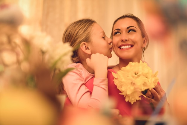 Foto menina bonitinha dando narcisos amarelos de buquê de mãe e beijando você.