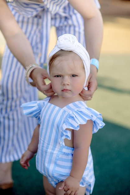 Foto menina bonitinha de 1 ano na praia no resort no verão com uma roupa da moda