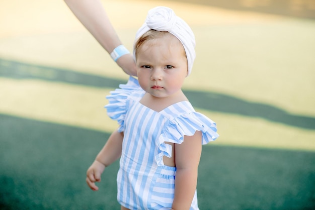 Foto menina bonitinha de 1 ano na praia no resort no verão com uma roupa da moda