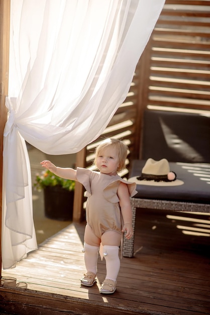 Foto menina bonitinha de 1 ano na praia no resort no verão com uma roupa da moda