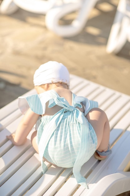 Menina bonitinha de 1 ano na praia no resort no verão com uma roupa da moda