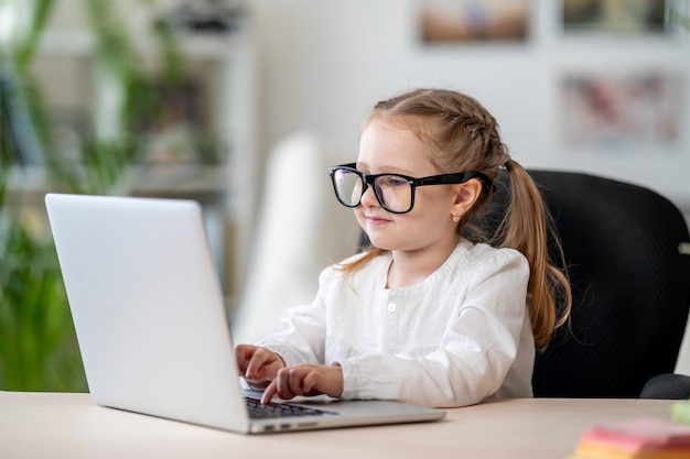 Menina bonitinha de óculos usando o conceito de e-learning digital portátil