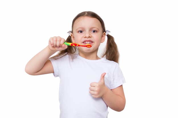 Menina bonitinha de pijama escovando os dentes com uma escova de dentes colorida