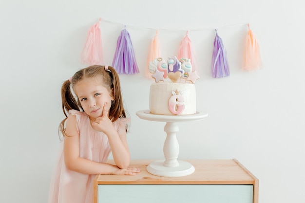 Menina bonitinha de vestido rosa com bolo de aniversário Celebração de seis anos Decoração de aniversário