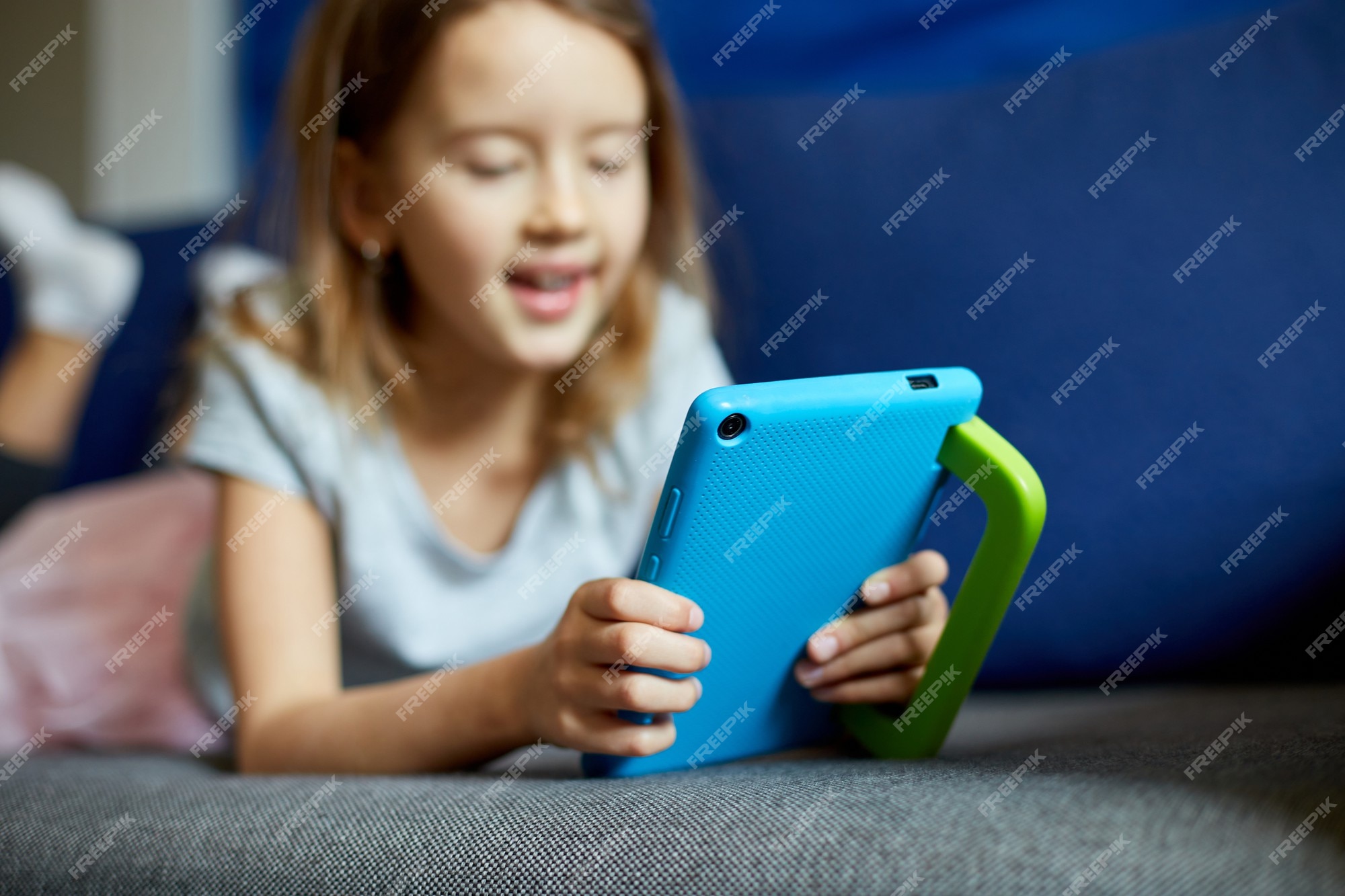 Menina sorridente, deitada no sofá confortável, desfrutando de jogar jogo  online no computador tablet digital viciada em tecnologia criança pequena  feliz usando aplicativos engraçados informações de navegação na web