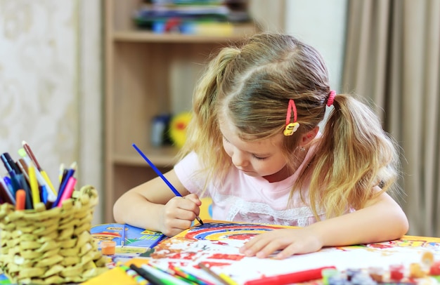 Menina bonitinha desenhando com lápis e canetas hidrográficas em casa