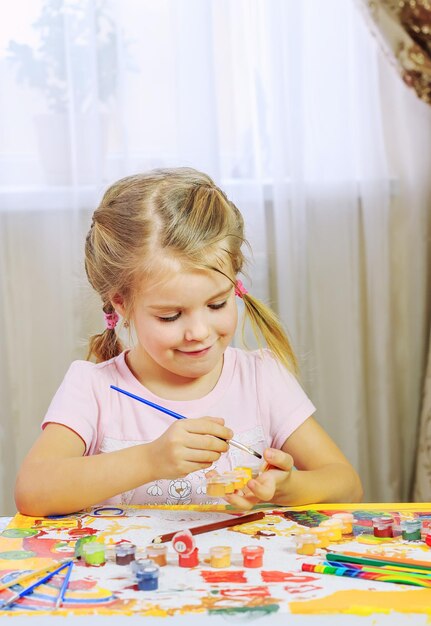 Menina bonitinha desenhando com lápis e canetas hidrográficas em casa