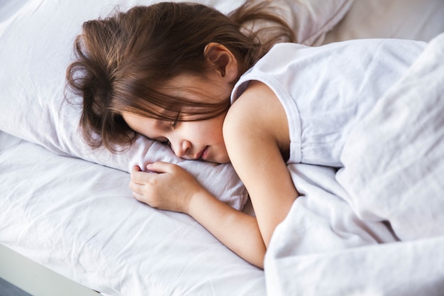 Menina bonitinha dormindo em sua cama em casa