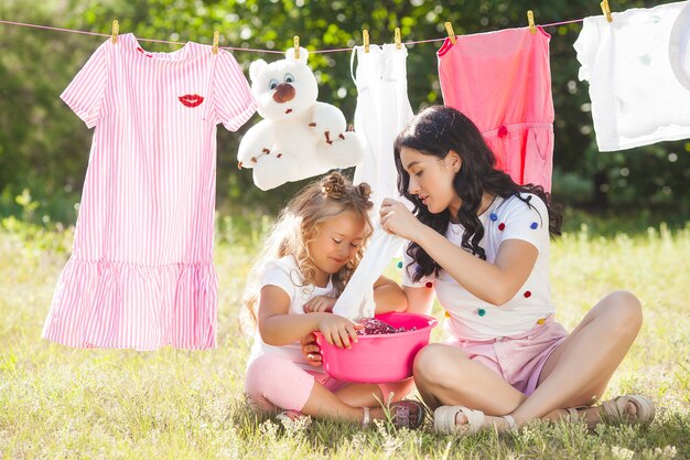 Menina bonitinha e a mãe lavando roupa