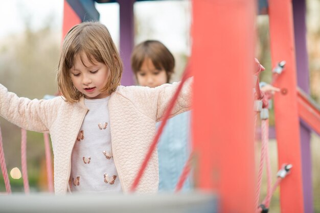 menina bonitinha e menino no parque infantil se divertindo e alegria enquanto brincava no playground em dia nublado de outono