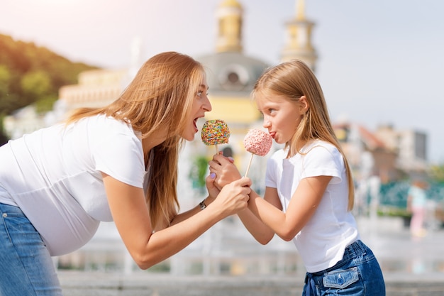 Menina bonitinha e sua mãe grávida comendo maçãs doces