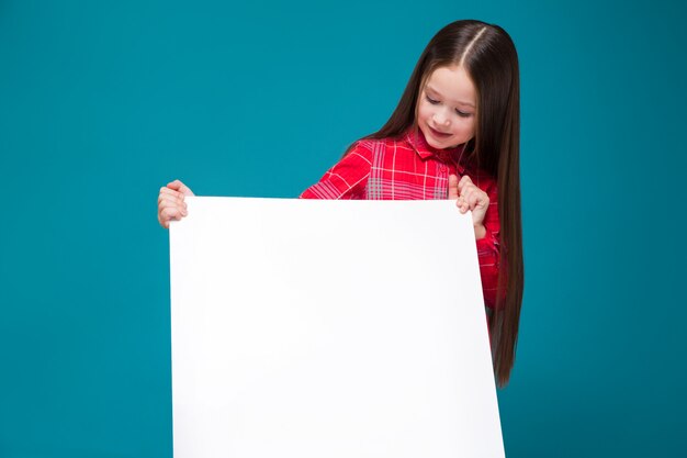 Menina bonitinha em camisa xadrez com cabelo moreno segurar papel claro