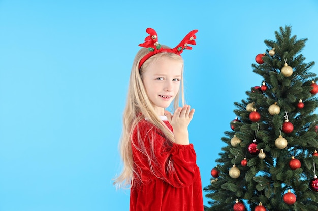 Menina bonitinha em fundo azul com árvore de natal