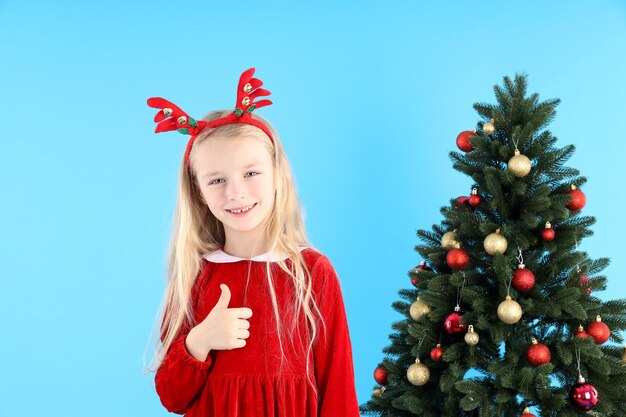 Menina bonitinha em fundo azul com árvore de Natal