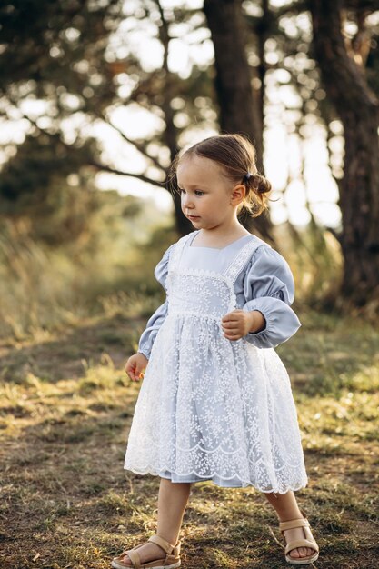 Menina bonitinha em lindo vestido andando na floresta