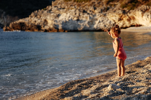 Menina bonitinha em pé perto do mar