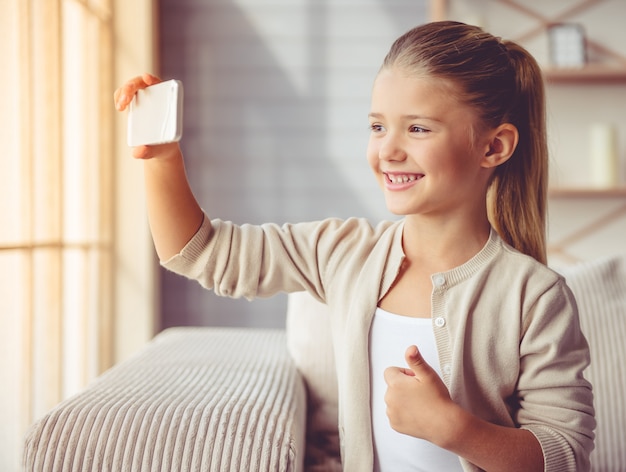 Menina bonitinha em roupas casuais está fazendo selfie