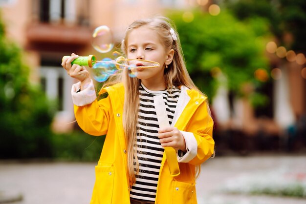 Menina bonitinha em tautumn na caminhada soprando bolhas de sabão Conceito de estilo de vida de descanso ativo na infância