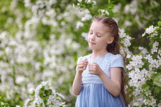 Menina bonitinha em vestido no jardim de macieira florescendo na primavera