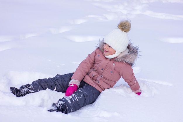 Menina bonitinha encontra-se em um monte de neve e sorria