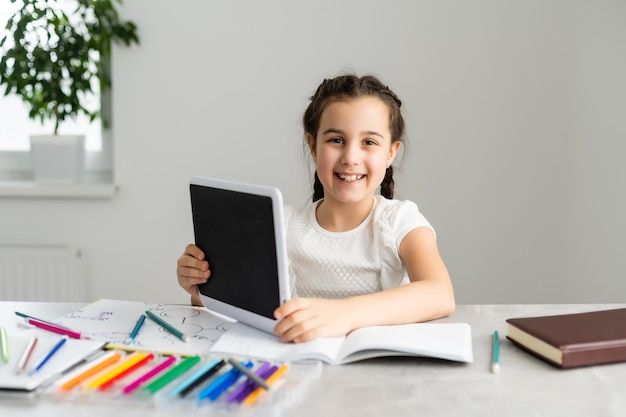 Menina bonitinha estudando em casa e sorrindo.