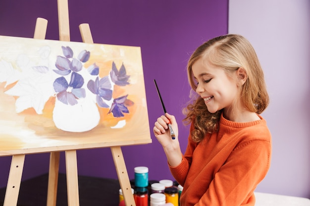 Menina bonitinha fazendo um desenho em uma tela dentro de casa