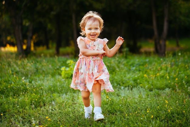 Menina bonitinha feliz correndo na grama do parque. Felicidade.