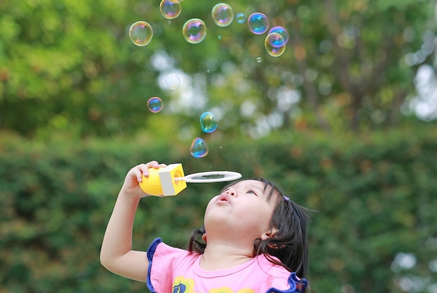 Menina bonitinha jogando bolha no parque.